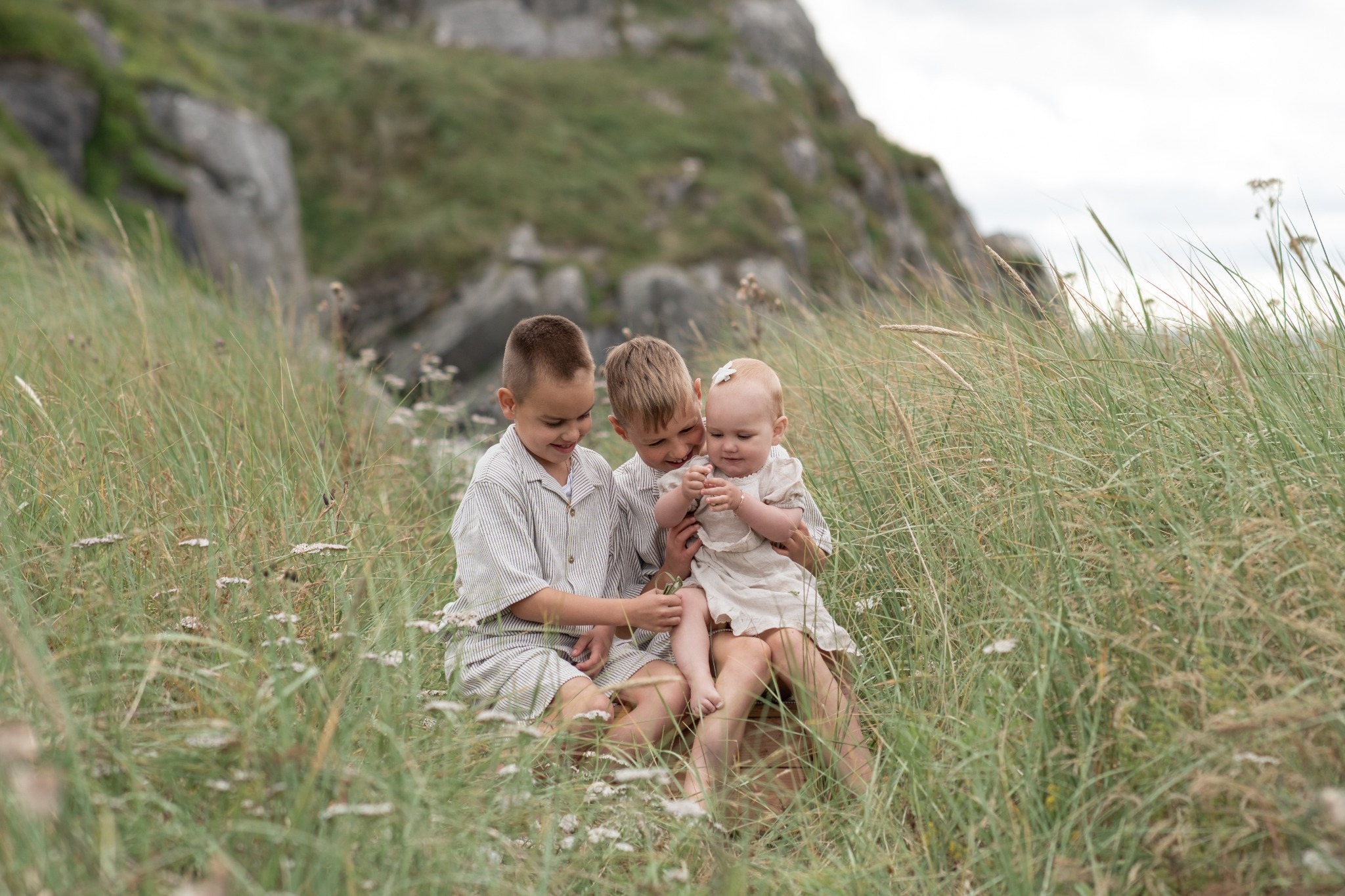 Tre sysken sit tett saman i strandgraset